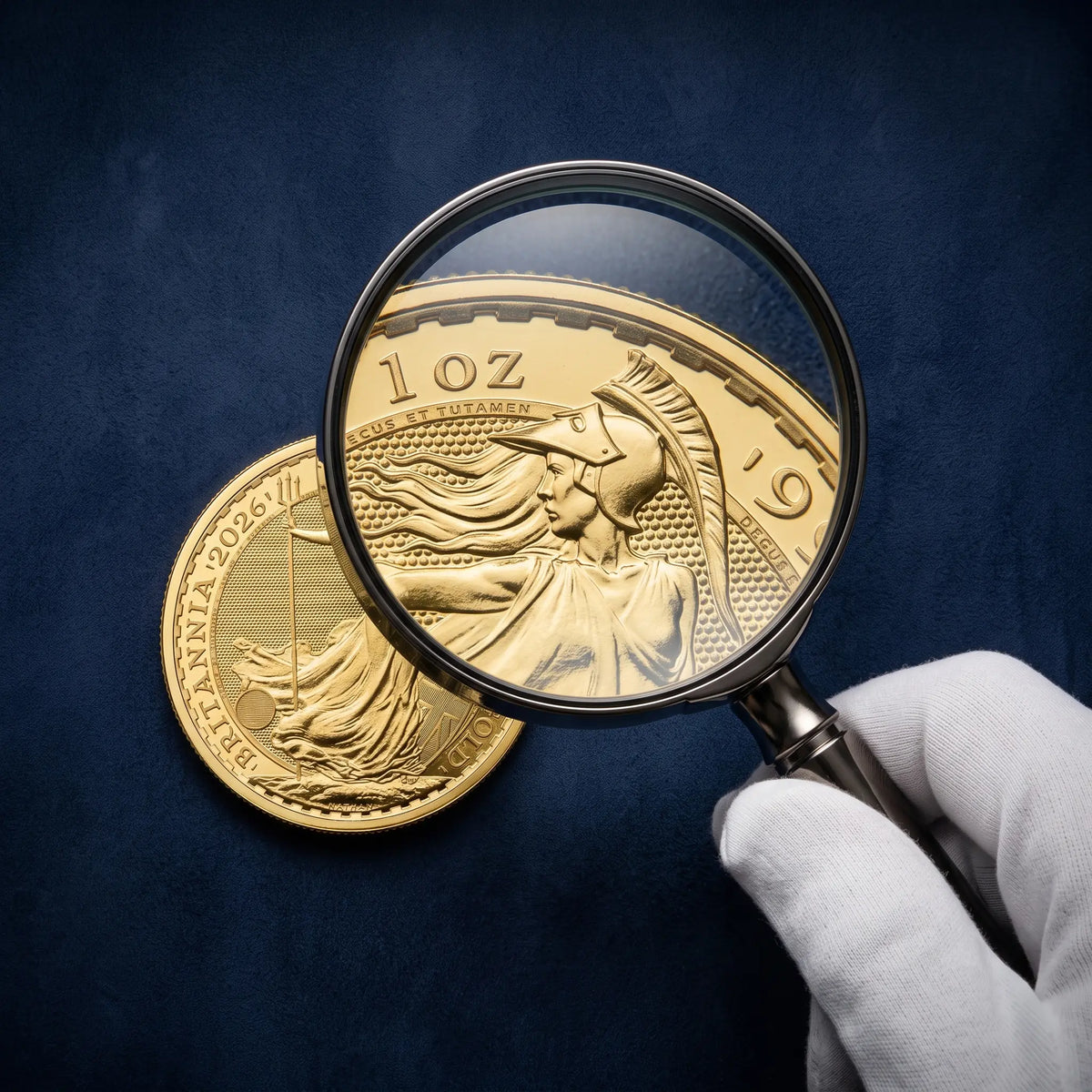 Loose gold Britannia bullion coin under a magnifying glass, inspected at Gold Tier Advisory